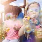 Two cute girls blowing the soap bubbles